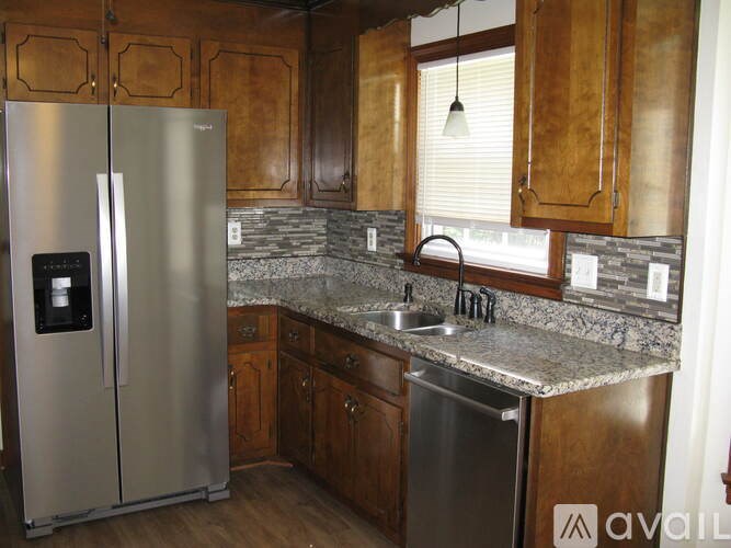 A kitchen with a stainless steel refrigerator and wooden cabinets.
