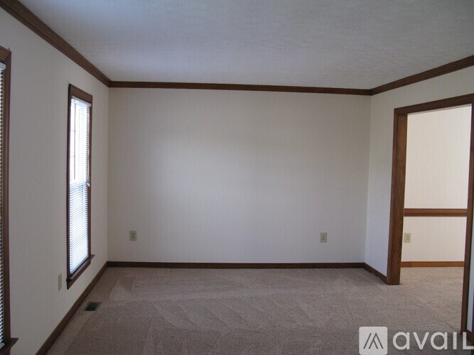 A room with a carpeted floor and a window on the left side.