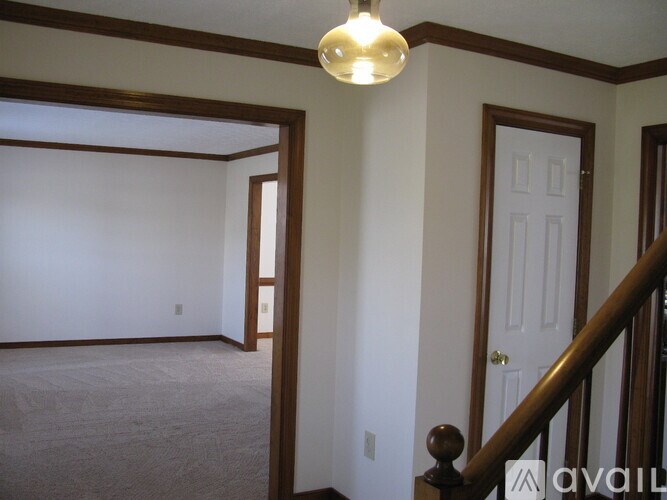 A room with a carpeted floor and a wooden staircase.