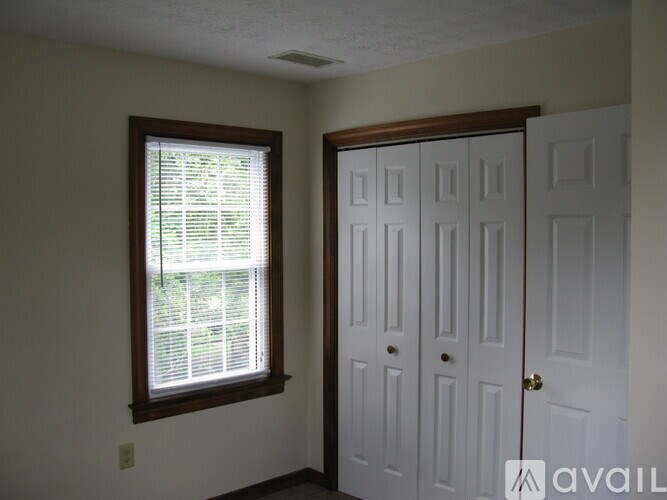 A room with a white door and a window with blinds.