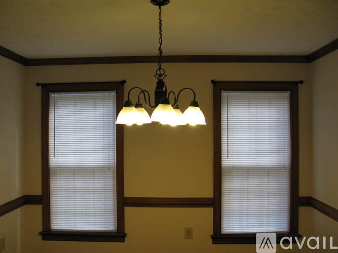 A room with a ceiling fan and two windows.