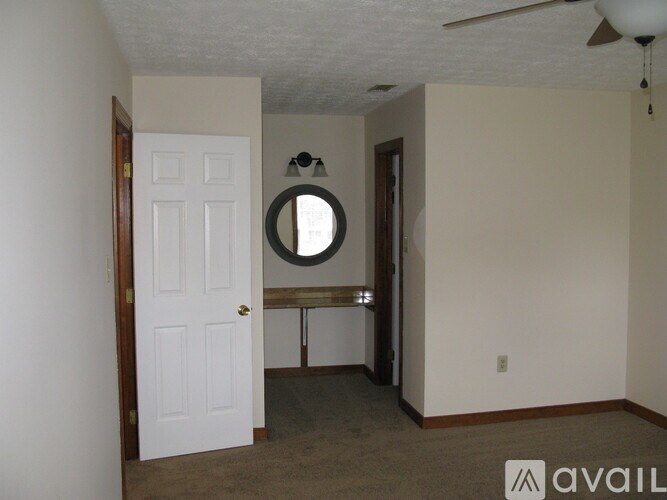 A room with a white door and a round mirror on the wall.