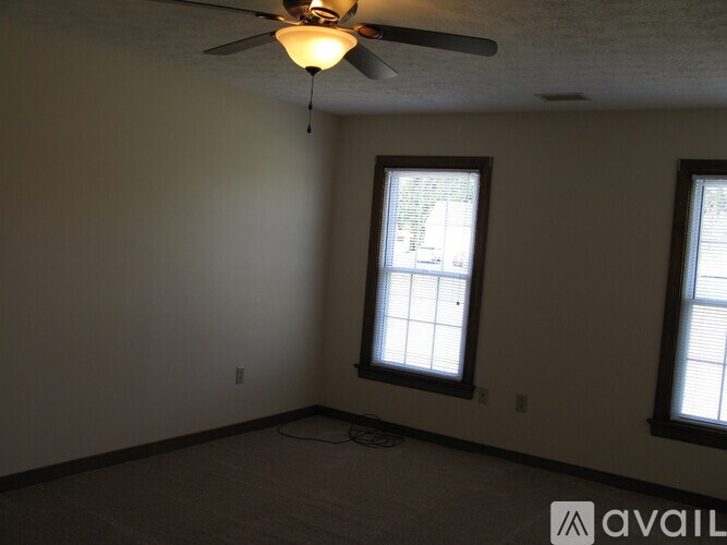 A room with a ceiling fan and two windows.