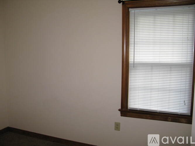 A window with white blinds in a room with a light colored wall.