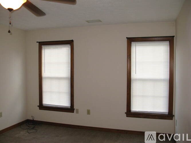 A room with two windows and a ceiling fan.