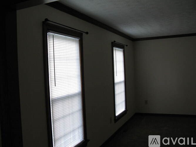 Two windows with blinds in a room with white walls.