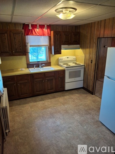 A kitchen with wooden cabinets and a white stove top oven.
