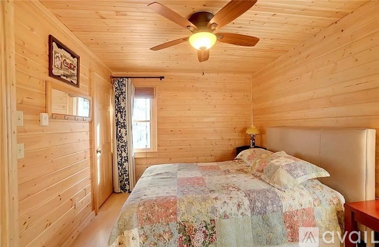 A bedroom with a bed, a ceiling fan, and a window.