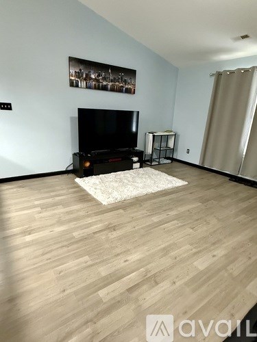 A living room with a television and a rug on the floor.