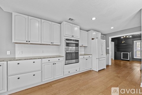A kitchen with white cabinets and a wooden floor.