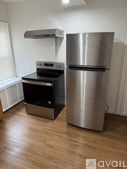 A stainless steel refrigerator stands next to a black stove in a kitchen.