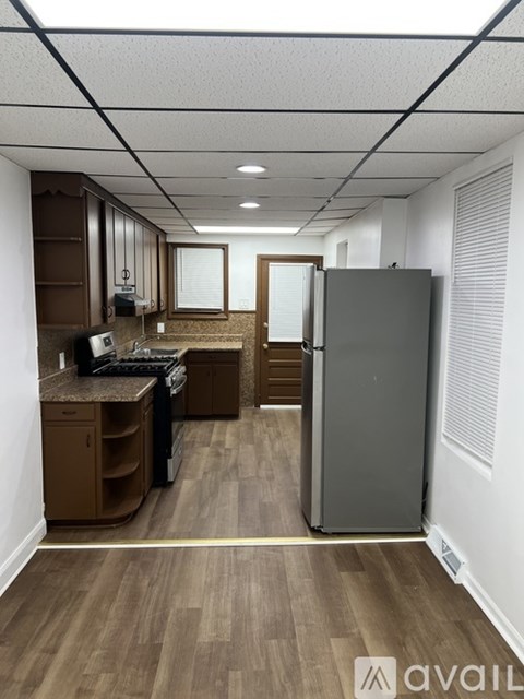 A kitchen area with a refrigerator, sink, and cabinets.