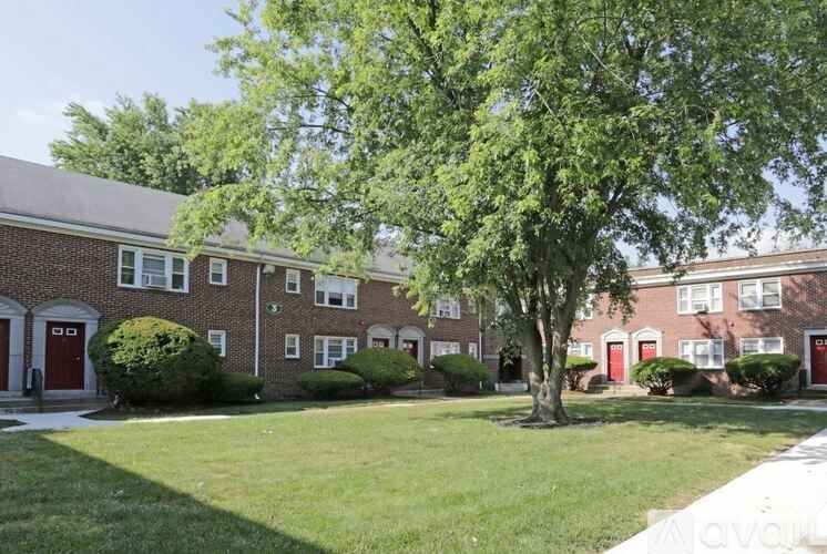 A tree in front of a brick building with red doors.