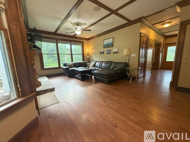 A living room with a black leather couch and wooden floors.