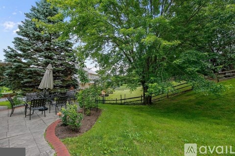 A patio with a table and chairs is surrounded by greenery.