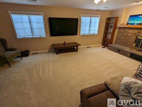 A living room with a flat screen TV mounted on the wall and a fireplace with a brick surround.