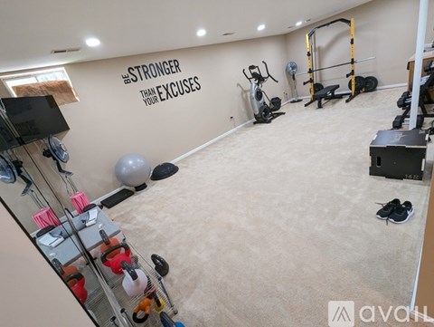 A gym with a wall that says "STRONGER THAN YOUR EXCUSES" and various exercise equipment.