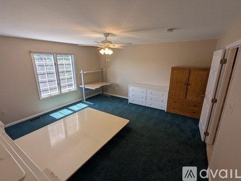 A bedroom with a bed, a ceiling fan, and a door.