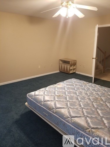 A bedroom with a bed, a ceiling fan, and a storage box.