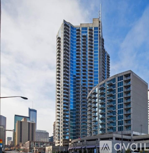 A tall building with blue glass windows stands in front of other buildings.