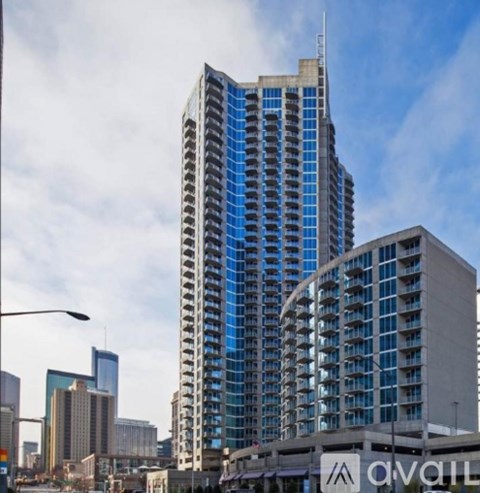 A tall building with blue glass windows stands in front of other buildings.