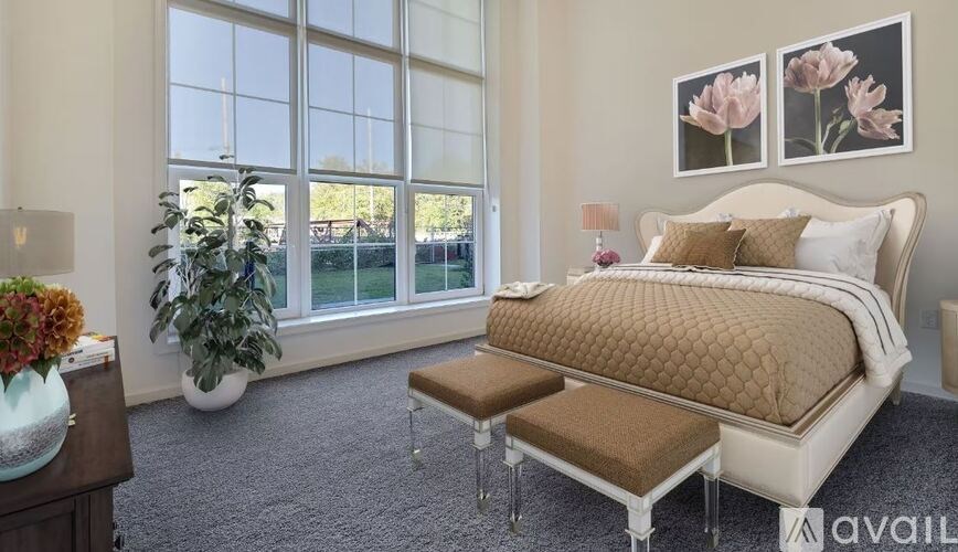A bedroom with a large bed, a bench, and a vase of flowers.