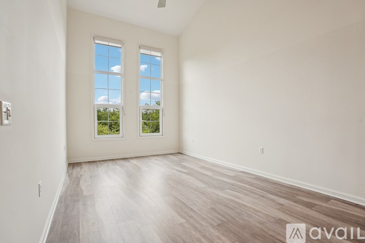 A spacious room with two windows and wooden flooring.