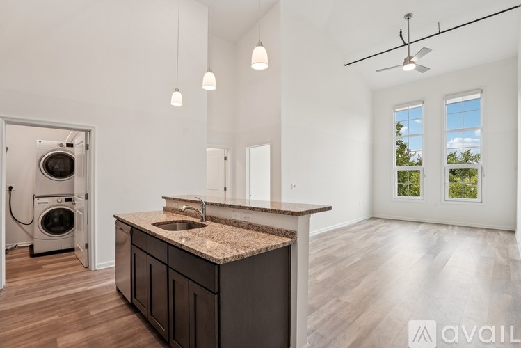 A modern kitchen with a large island and a washer and dryer built into the wall.