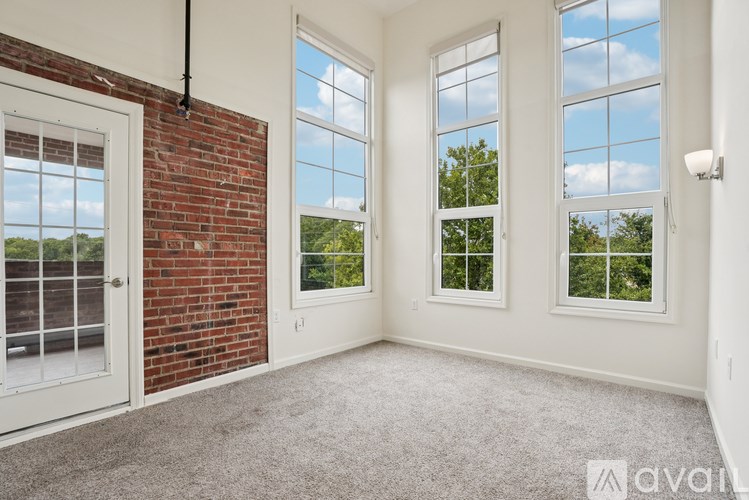 A room with a brick wall and three windows.