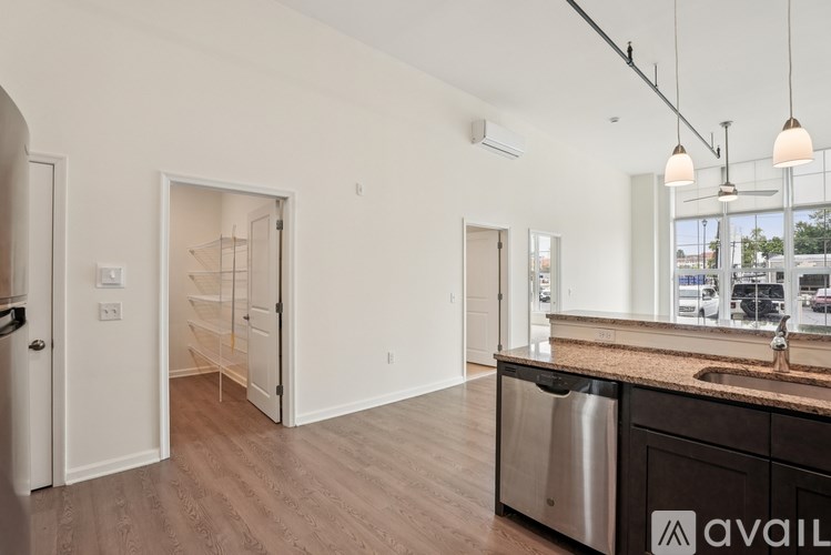 A kitchen with a sink, a window, and a stainless steel trash can.