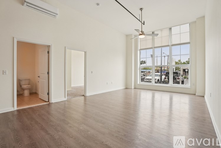 A spacious room with wooden flooring and a view of the city through large windows.