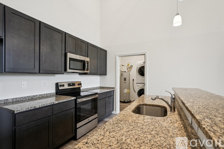 A kitchen with black cabinets and a granite countertop.