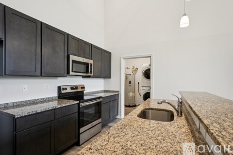 A kitchen with black cabinets and a granite countertop.