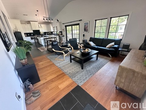 A living room with a black couch and a wooden floor.