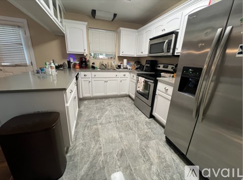 A kitchen with white cabinets and a marble floor.