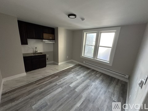A spacious kitchen with dark wood cabinets and a large window.