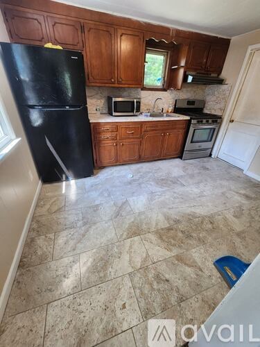 A kitchen with a black fridge and brown cabinets.