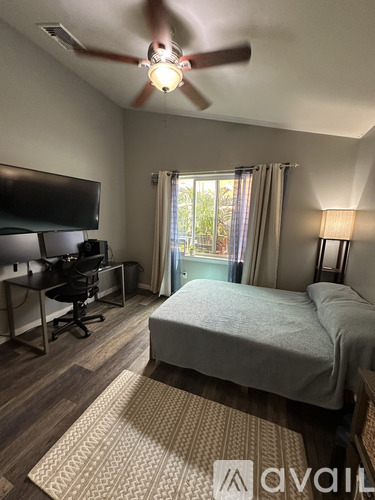 A bedroom with a bed, desk, and television.