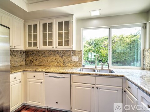 A kitchen with white cabinets and a granite countertop.