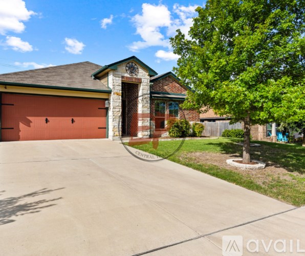 A house with a garage and a tree in front.
