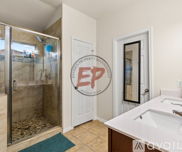 A bathroom with a glass shower door and a white sink.