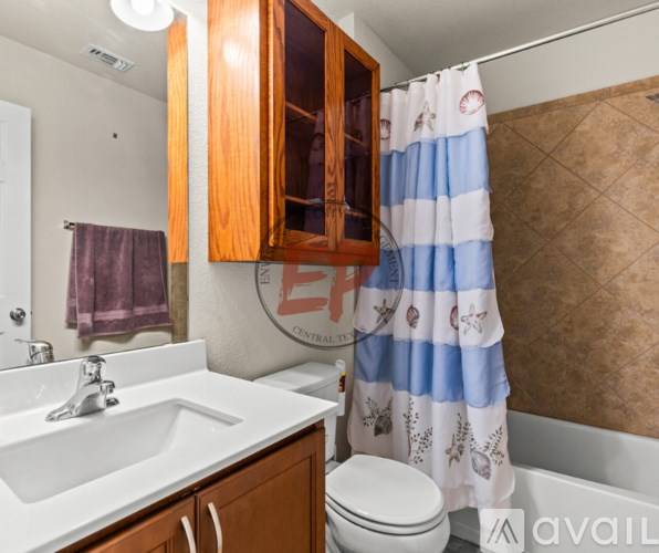 A bathroom with a white sink, wooden cabinets, and a blue and white striped shower curtain.