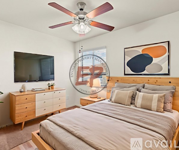 A bedroom with a large bed, a ceiling fan, and a painting on the wall.