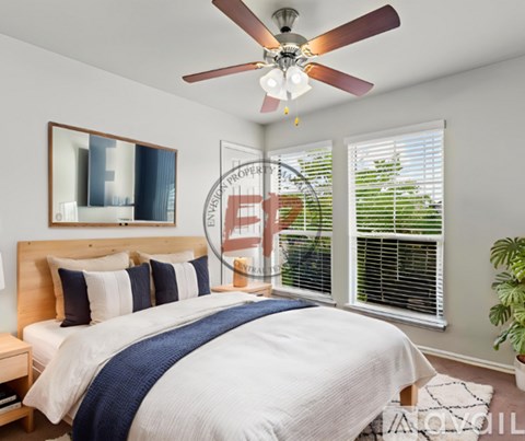 A bedroom with a large bed and a ceiling fan.