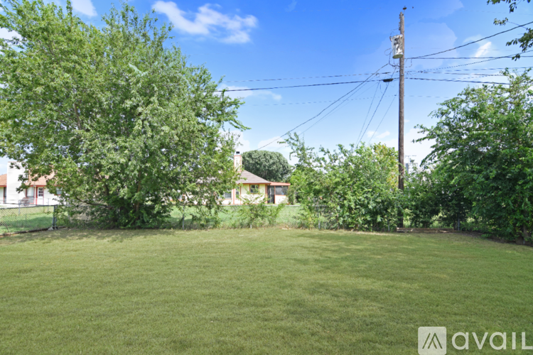 A house with a white roof and a chimney is surrounded by a grassy yard.