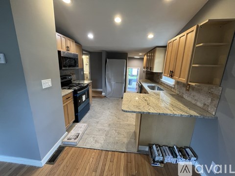 A kitchen with a granite countertop and wooden cabinets.