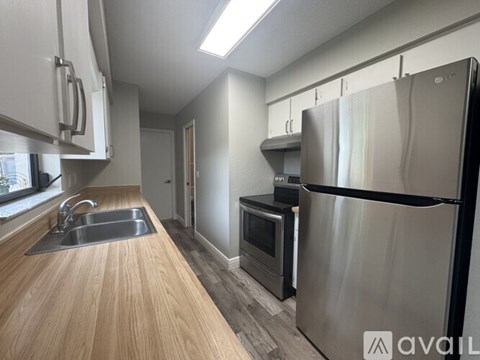 A kitchen with a wooden counter top and stainless steel appliances.