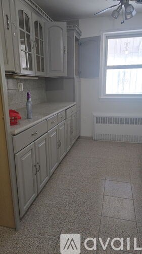 A kitchen with white cabinets and a tiled floor.