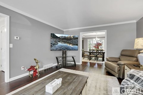 A living room with a grey wall and a painting of a lake.