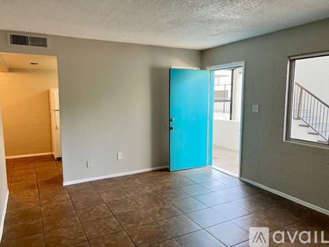 A room with a blue door and brown tile flooring.